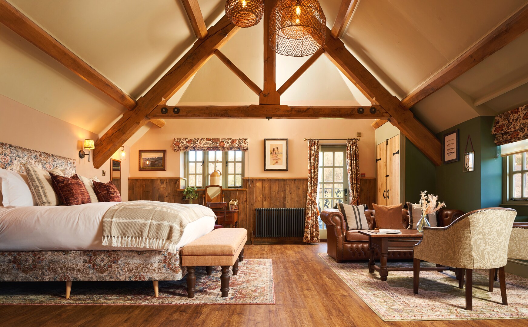 Bedroom with exposed wooden beams, a large bed, and a sitting area.