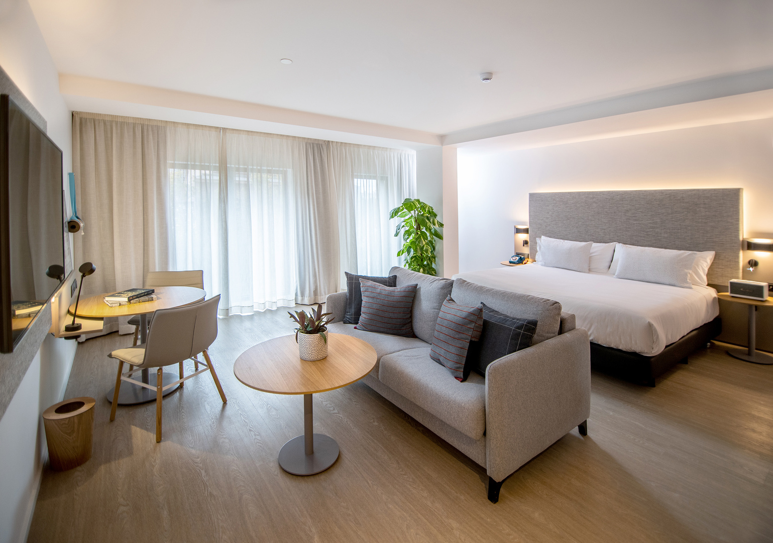 Hotel room with a bed, sofa, and small table.