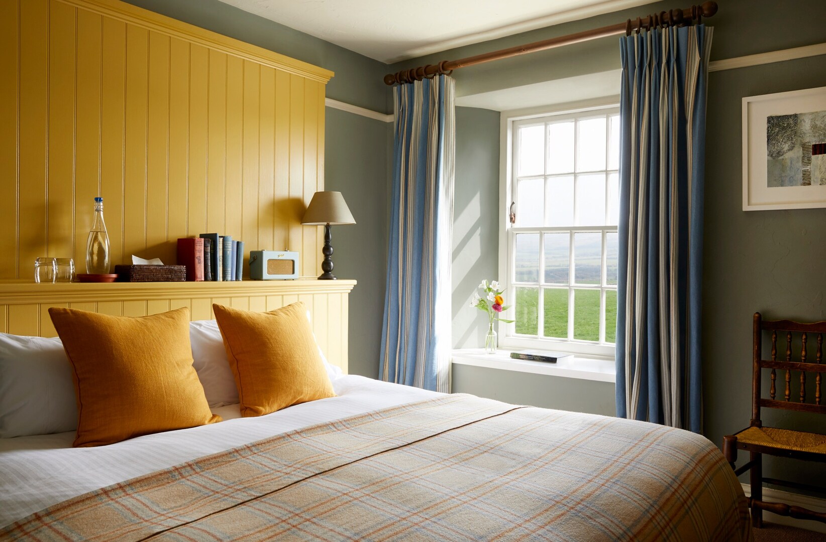 Bedroom with yellow headboard and plaid throw.
