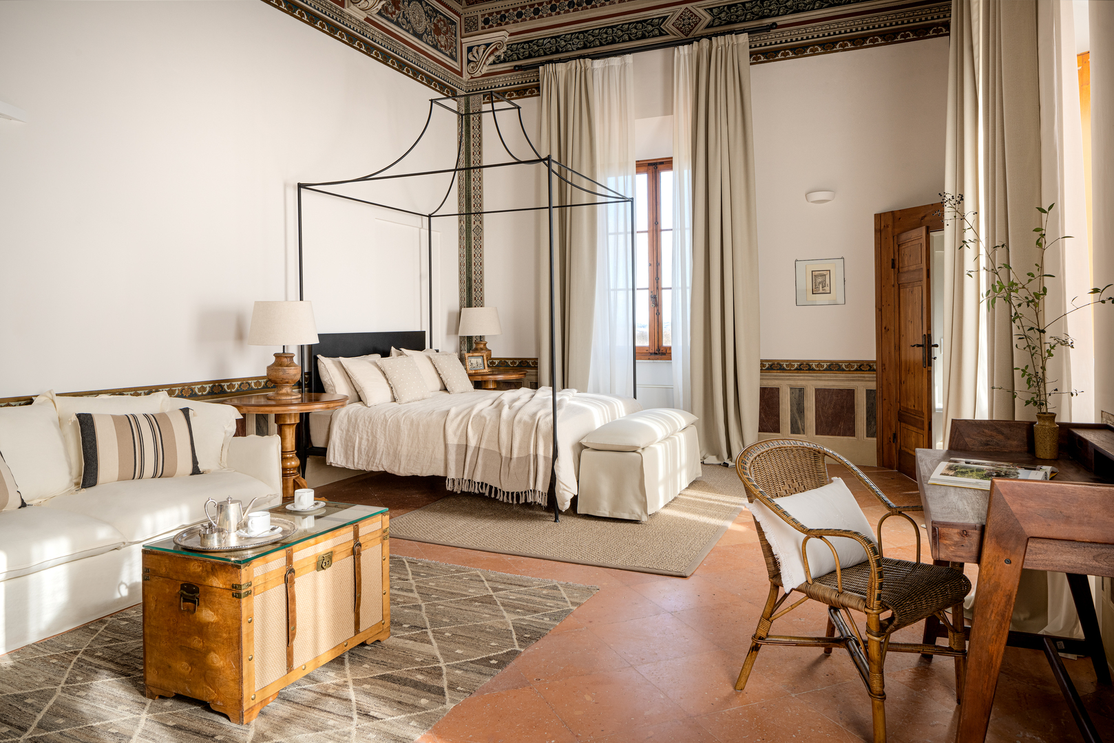 Bedroom featuring a four-poster bed, a seating area, and a writing desk.