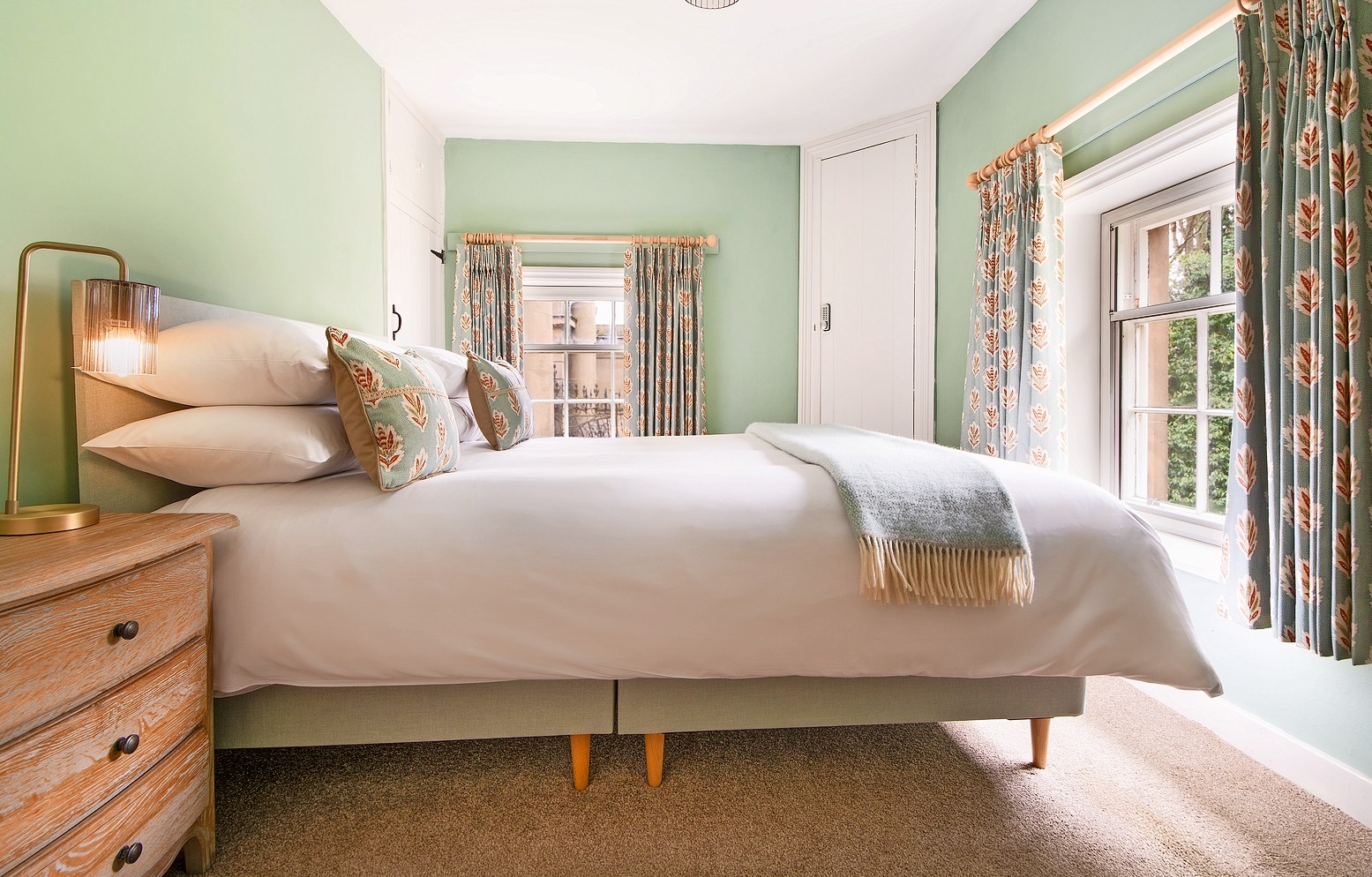 Bedroom with a double bed, light green walls, and patterned curtains.