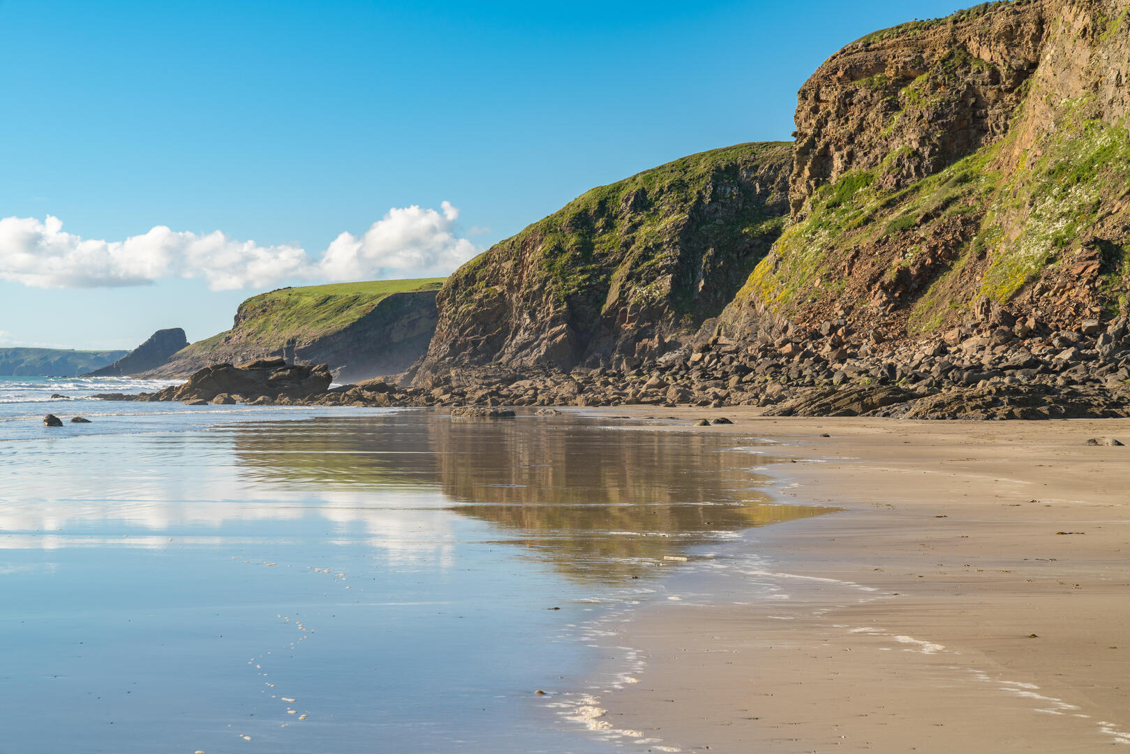 Sandy beach with rocky cliffs and ocean.