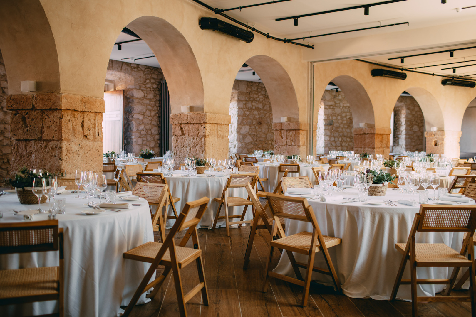 Wedding reception tables set in a stone hall with arched ceilings.